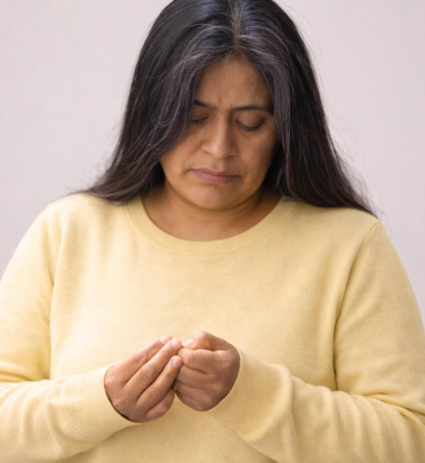 Woman closely examining her fingers with a worried expression suggesting repetitive checking or intrusive thoughts