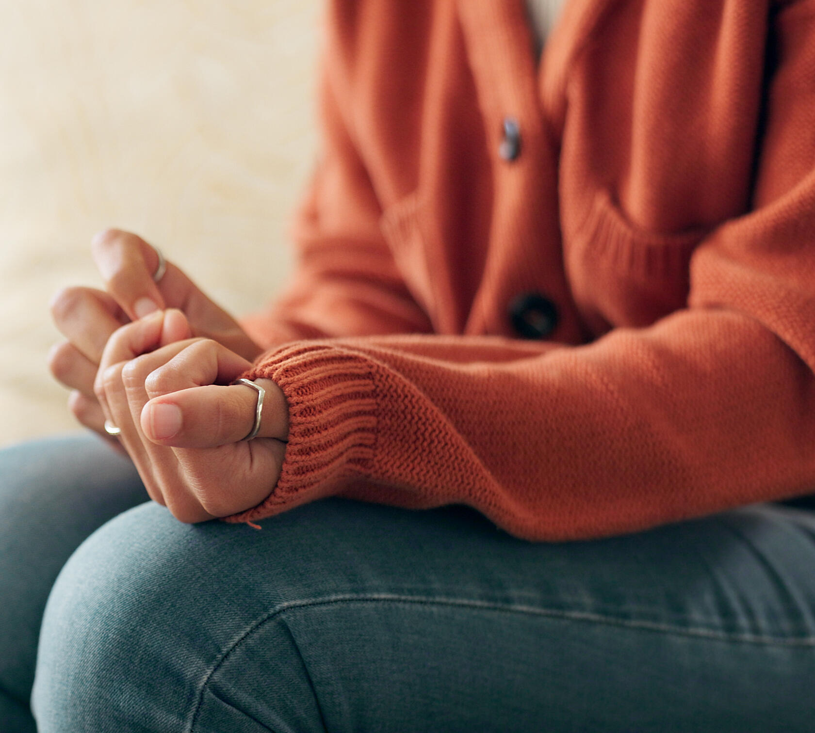Person sitting with hands tightly clasped, showing tension and distress associated with PTSD and trauma